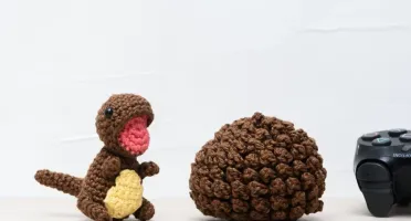 Ovo com filhote de dinossauro marrom em amigurumi