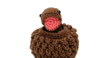 Ovo com filhote de dinossauro marrom em amigurumi